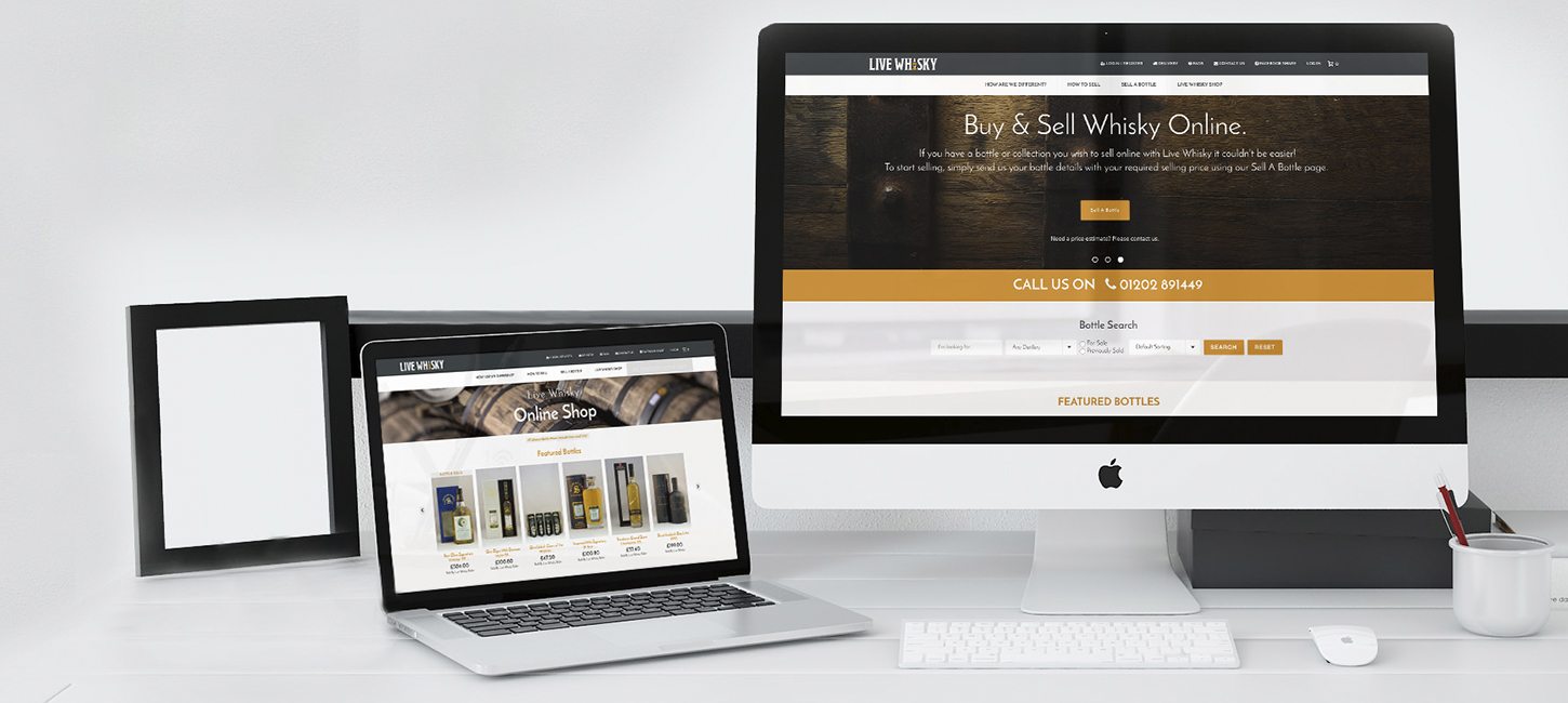 Mac and laptop on a desk showing live whisky website